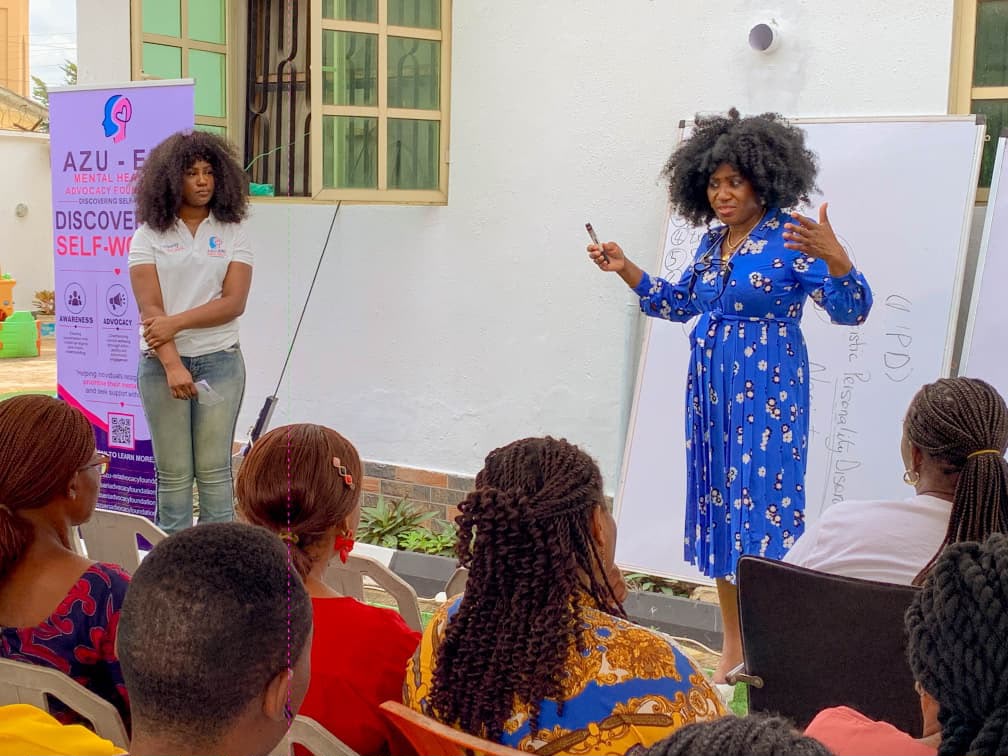 A speaker presenting beside the Azu-Eri banner at the roadshow